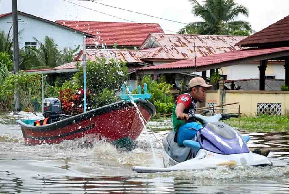 Penduduk kampung menggunakan jet ski untuk membawa bot di atas jalan raya di Kampung Tok Oh yang dinaiki air disebabkan banjir di sekitar kawasan Tumpat. - Foto: Bernama