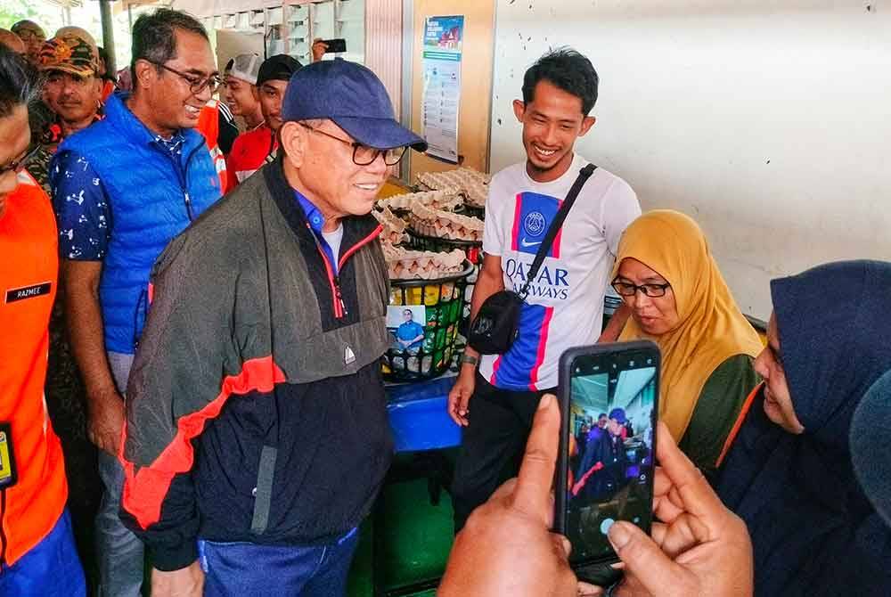 Wan Rosdy (tengah) menyantuni mangsa banjir di SK Teluk Ira pada Jumaat.
