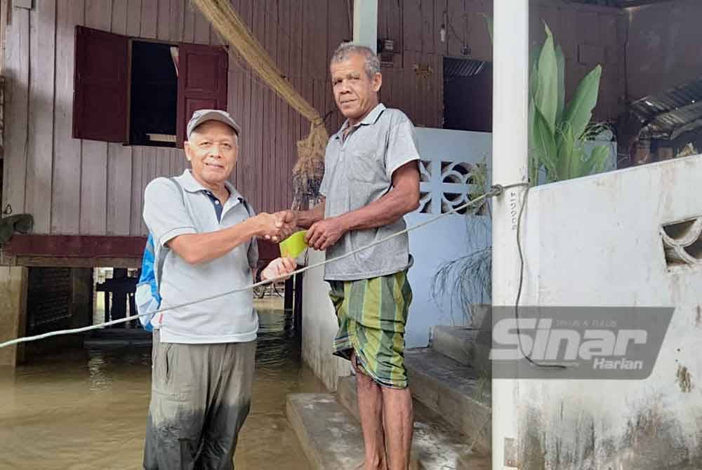 Bantuan disampaikan oleh Muhammad Nasir (kiri) kepada penduduk di Kampung Derdap. Foto SINAR HARIAN