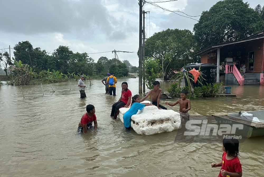 Muhammad Nasir (kiri) yang turut mengharungi banjir di Kampung Derdap bagi menyampaikan bantuan. Foto SINAR HARIAN