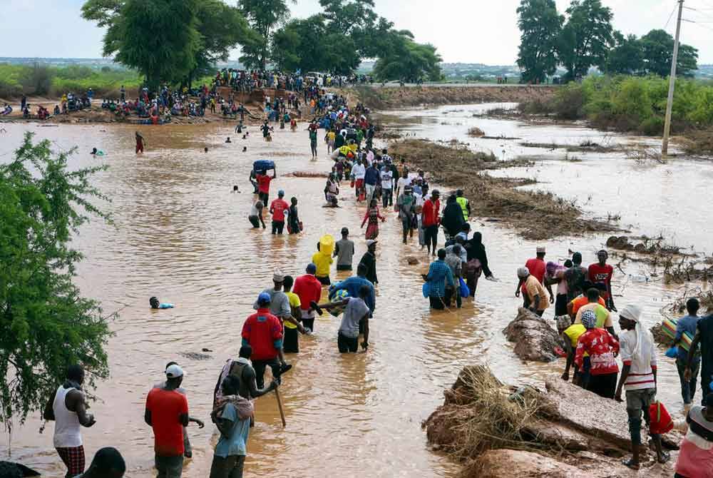 Penduduk terpaksa meredah banjir selepas jalan raya utama di Mororo musnah.