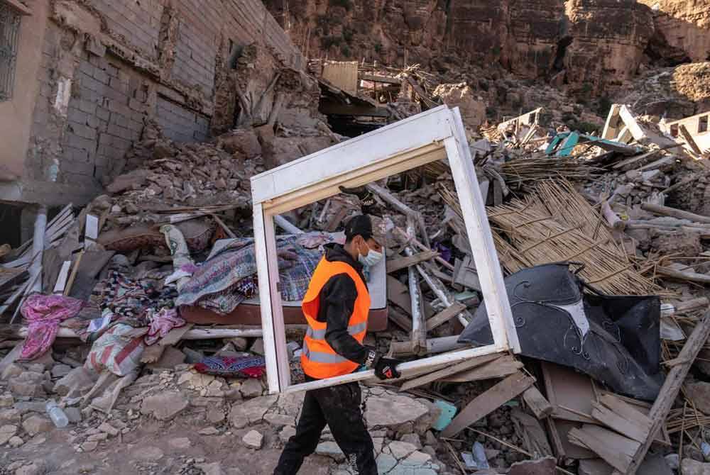 Seorang sukarelawan mengumpulkan perabot di sebuah rumah yang musnah akibat gempa di bandar Imi N'Tala di luar Marrakesh pada September lalu.