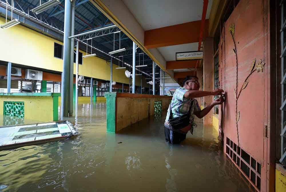 Muhammad Navi memantau keadaan sekitar sekolah yang ditenggelami air disebabkan banjir yang berlaku sejak 26 Disember lalu di Sekolah Menengah Ugama (Arab) Al-Falah di Kampung Siram pada Sabtu. - Foto: Bernama