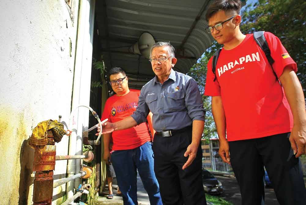 Seh Yong (tengah) menunjukkan sambungan paip haram di PPR Lobak.