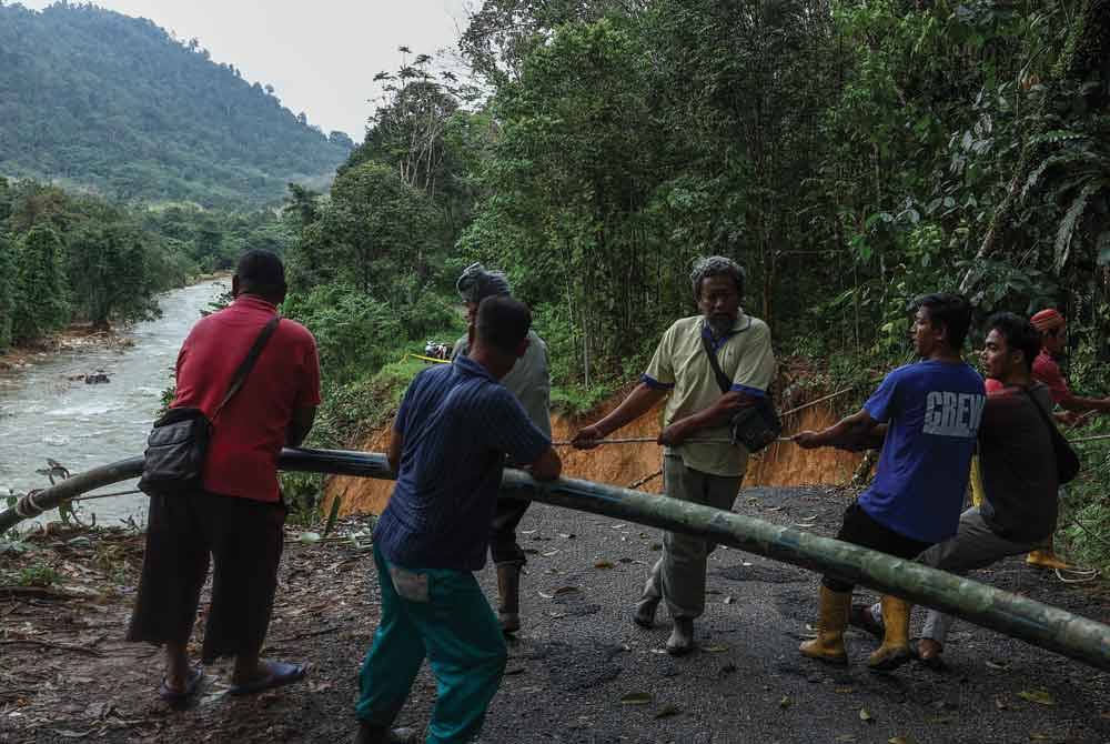 Penduduk bergotong-royong untuk menarik naik dan membaiki paip air tandak itu. - Foto Bernama