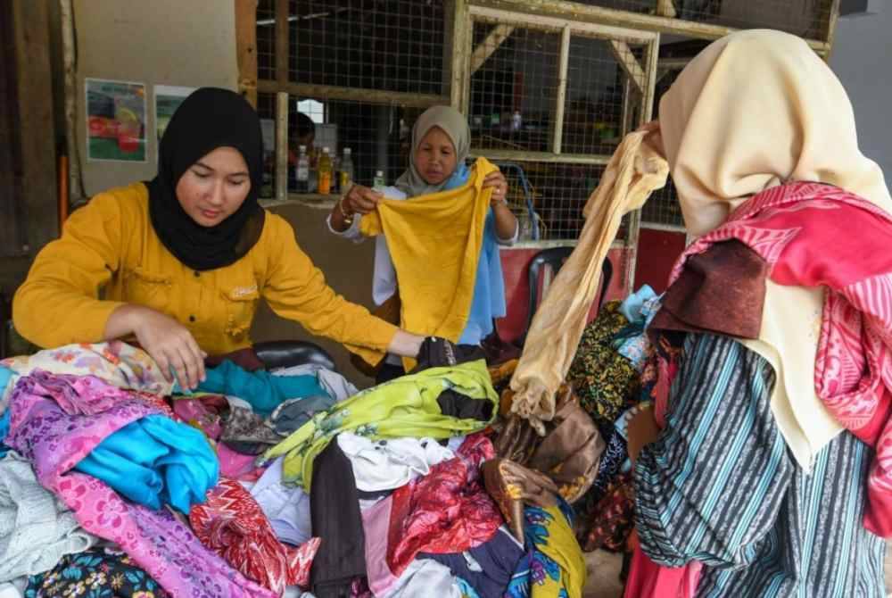 Mereka datang awal bukan untuk minum pagi di satu-satunya kedai kopi di kampung itu, sebaliknya mahu mengambil baju terpakai yang disumbangkan oleh NGO kepada penduduk kampung yang terjejas akibat gelombang ketiga banjir. Foto Bernama