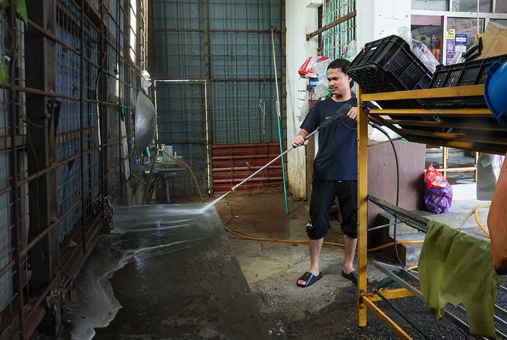 Pembantu membersihkan kedai yang dinaiki air selepas banjir melanda kawasan Kampung Ana ketika tinjauan pada Ahad. - Foto Bernama