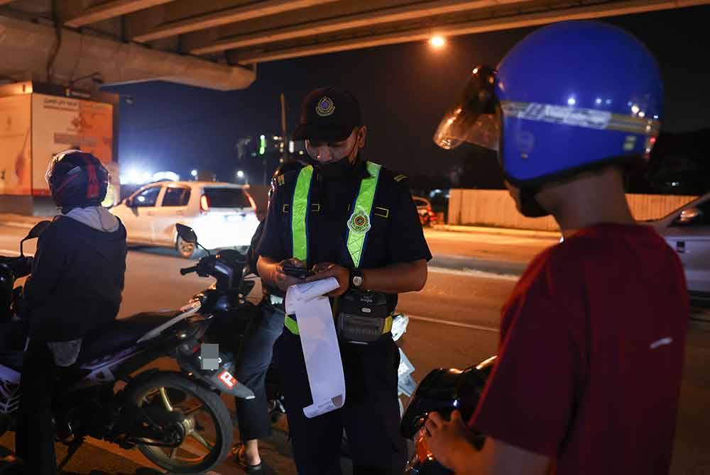 Anggota JPJ mengeluarkan saman terhadap penunggang motosikal yang melanggar undang-undang pada Operasi Ambang Tahun Baharu di sekitar Kota Bharu malam tadi. - Foto Bernama
