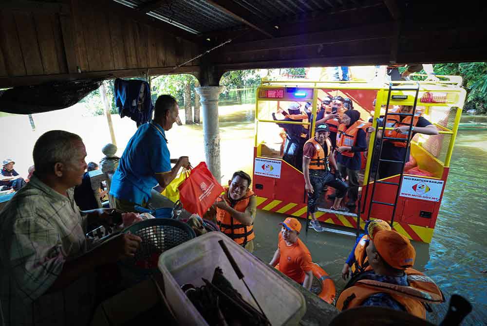 Sukarelawan Pertubuhan Kebajikan MCIO bersama Pejabat Pembangunan Negeri Kelantan, ICU JPM dan APM dibantu penduduk kampung mengagihkan bekalan makanan serta menyantuni kira-kira 50 mangsa daripada 11 keluarga di Kampung Bongor semalam. - Foto Bernama