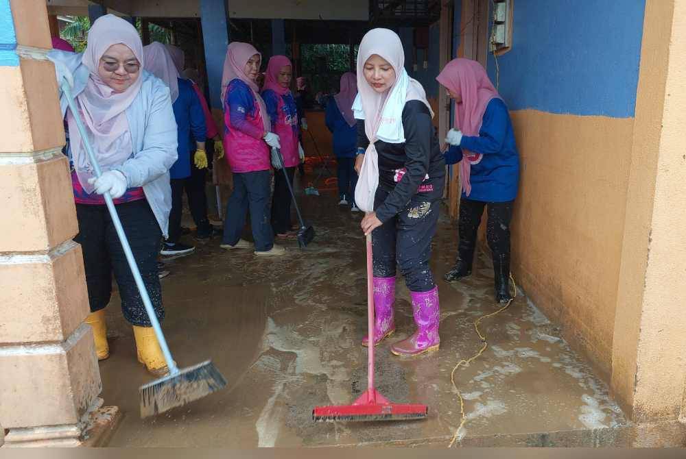 Nurul Amal (dua dari kanan) bersama sukarelawan Puteri UMNO membersihkan dewan pertubuhan bukan kerajaan (NGO) Kampung Pengkalan Ajal.