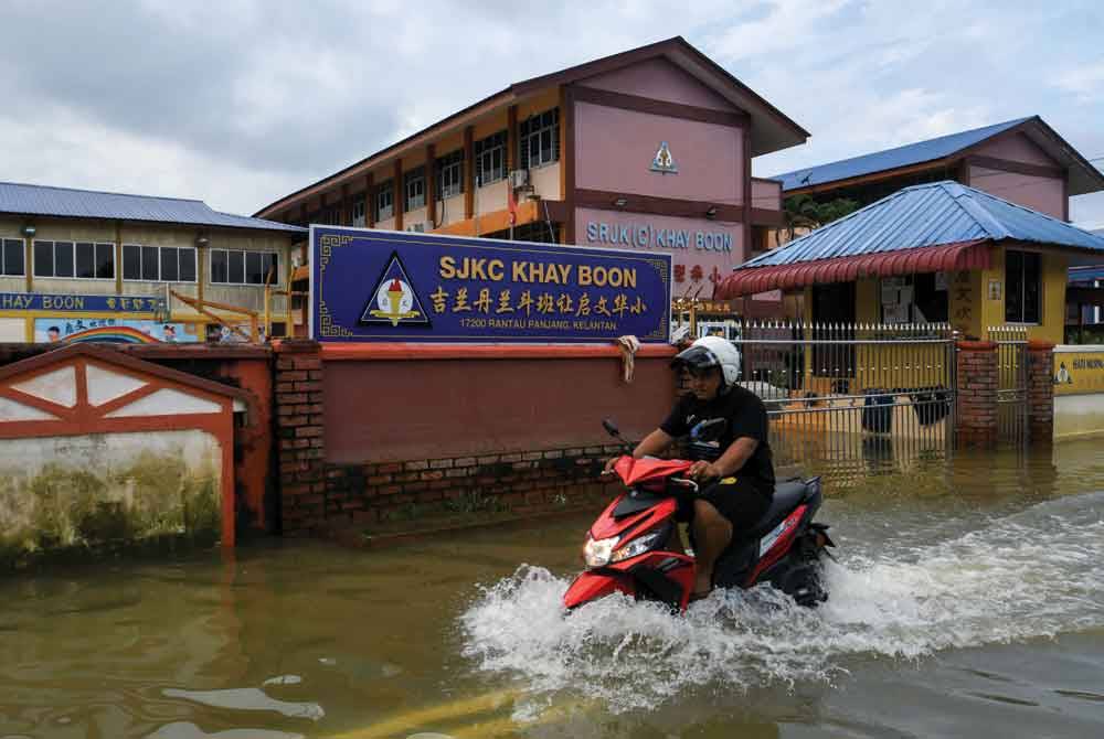 Penunggang motosikal merendah air di hadapan Sekolah Jenis Kebangsaan Cina Khay Boon, PAsir Mas berikutan kejadian banjir yang berlaku ketika tinjauan di Rantau Panjang pada Sabtu. Foto Bernama