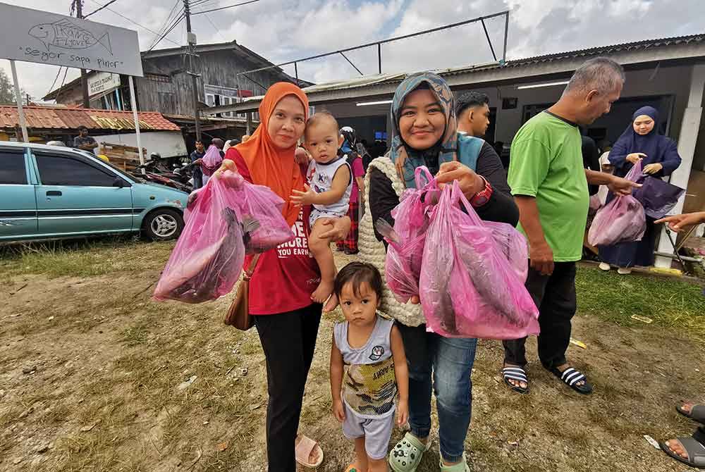 Norhidayah (dua dari kanan) menunjukkan ikan siakap yang dibeli dari premis jualan Ikan Flyover di Kuala Ibai pada Rabu.