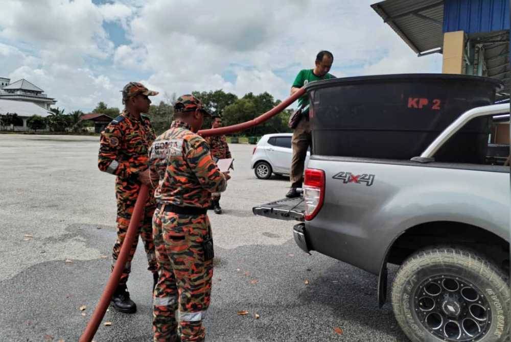 Anggota bomba membantu penduduk menadah air untuk diagihkan kepada mereka yang terjejas.