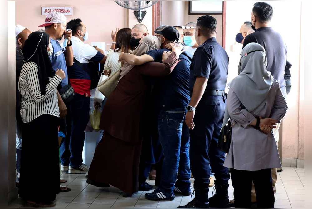 Sebahagian anggota Esscom berpelukan dengan ahli keluarga mereka sebaik tiba di Mahkamah Tinggi bagi pertuduhan kes bunuh pemandu e-hailing hari ini. Foto Bernama