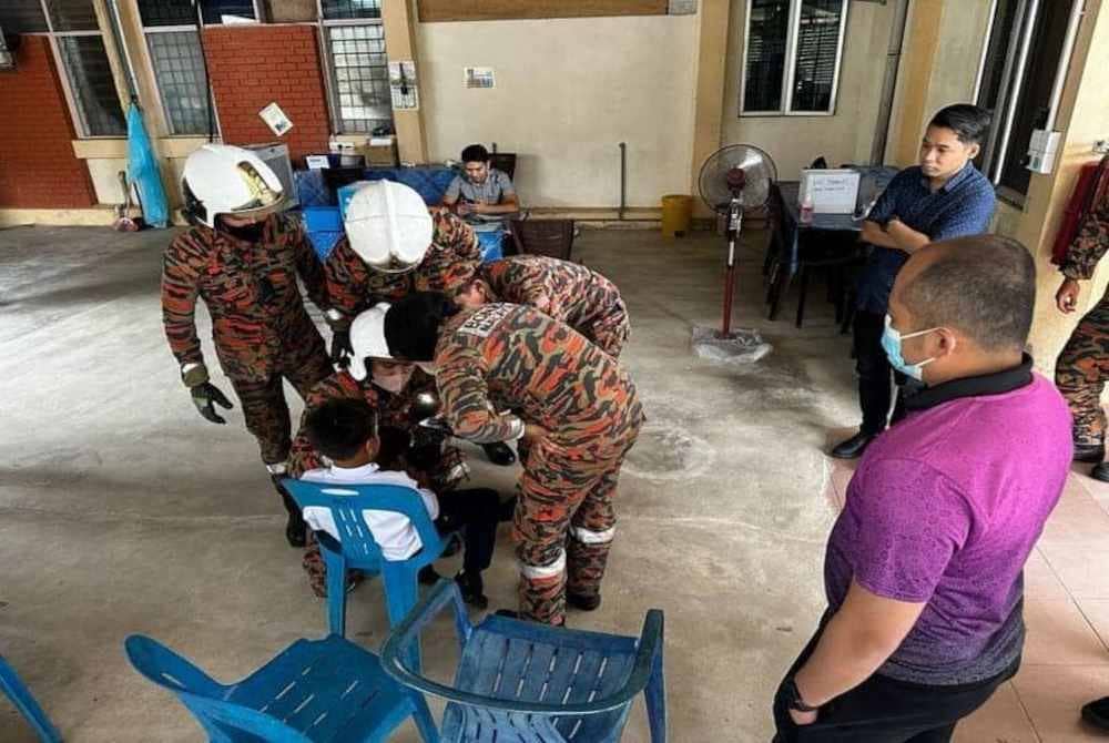 Anggota bomba mengeluarkan jari murid yang tersangkut pada tombol pintu pada Khamis.