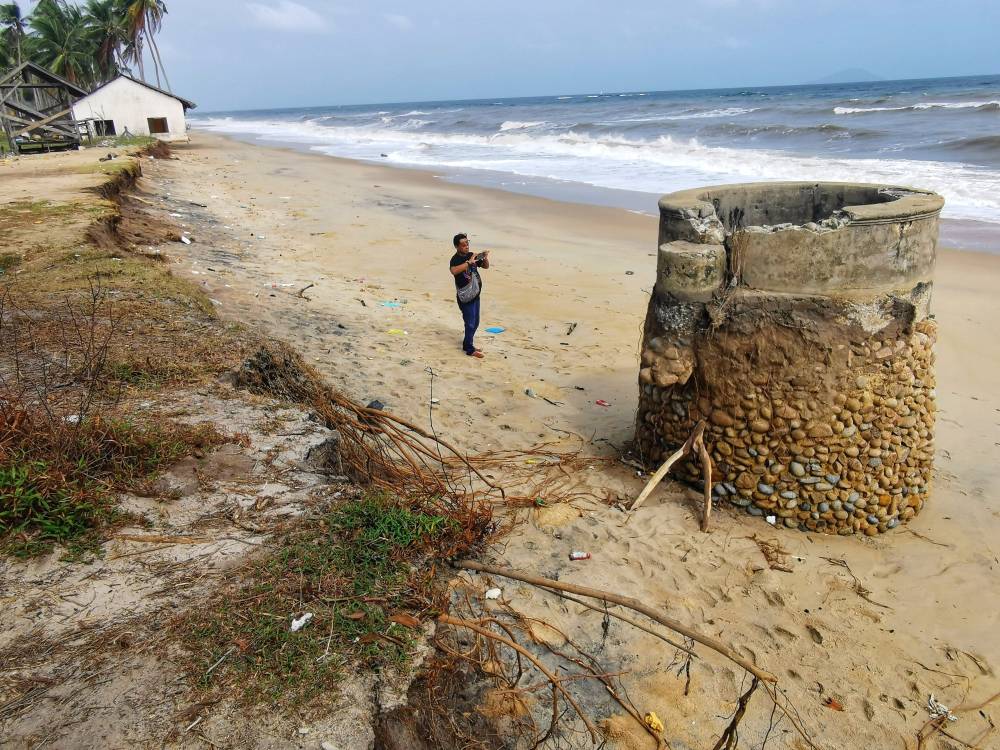 Seorang pengunjung merakam gambar perigi yang bakal ditelan ombak akibat masalah hakisan yang semakin meruncing di kawasan Kampung Mengabang Kapal, Batu Rakit, di Kuala Nerus.