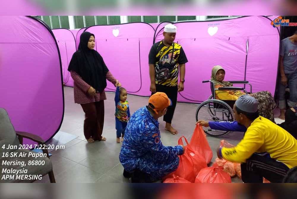 Anggota Pertahanan Awam Malaysia (APM) mengagihkan bantuan makanan kepada mangsa banjir di PPS Sekolah Kebangsaan (SK) Air Papan, Mersing pada Khamis. Foto APM Johor