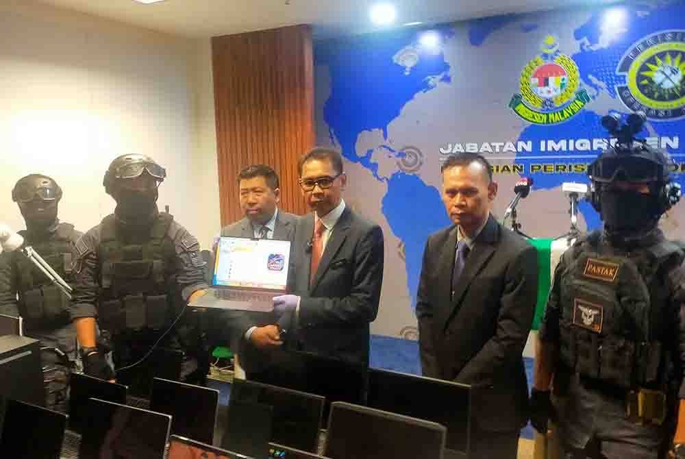 Jafri (tiga dari kanan) menunjukkan komputer riba yang mempromosikan penipuan perjudian dalam talian semasa serbuan khas JIM di dua premis di Bangsar dan Ampang pada Khamis.