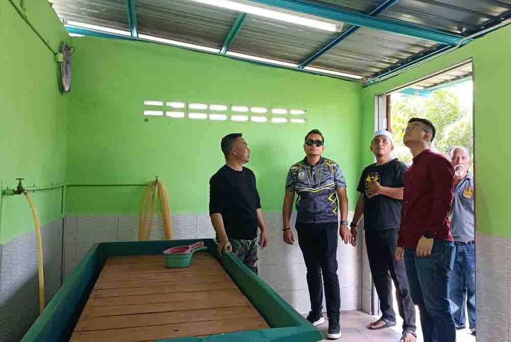 Steven (kanan) meninjau tempat mandi jenazah yang disediakan kariah surau hasil kutipan daripada penduduk.