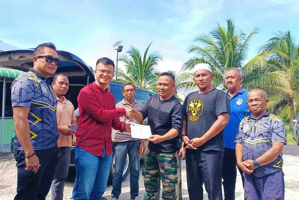 Steven (dua dari kiri) menyerahkan geran kenderaan kepada Ahmad Jamil sebagai gimik penyerahan van jenazah milik Surau Nurul Huda di Taman Tasek Putra pada Jumaat.