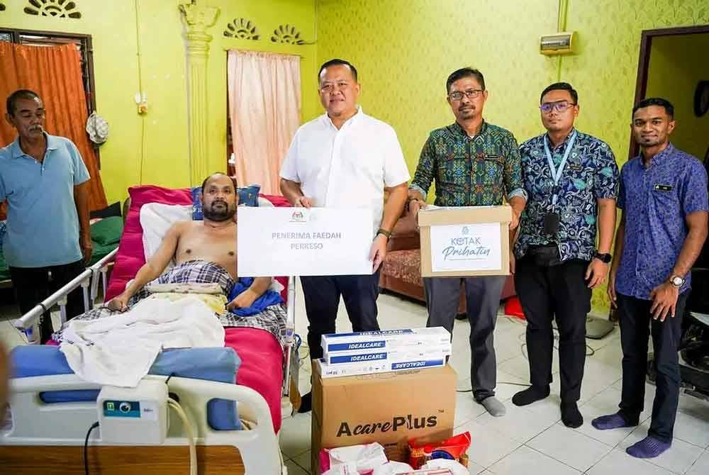 Rizam (empat dari kanan) menyampaikan sumbangan Perkeso kepada Nurul Nizam semasa kunjungan mesra di kediamannya di Kampung Tebuk Mufrad di sini pada Jumaat.