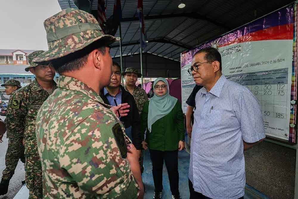Mohamed Khaled (kanan) mendengar penerangan daripada pegawai bertugas ketika hadir di PPS Sekolah Rendah Agama Bersepadu hari ini. Foto Bernama