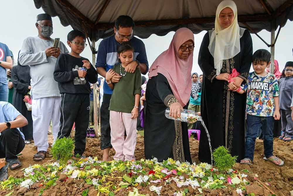 Siti Nooriah Hassan, 69, (tiga, kanan) menyiram air mawar di atas pusara anaknya, Allahyarham Siti Nor Hafiza Kamarudin, 40, di Tanah Perkuburan Islam Raudathul Sakinah, Taman Selasih, Jalan Kuala Lumpur-Karak hari ini. Turut kelihatan suami Allahyarham Mohd Roshdi Ramli (tiga, kiri) serta anak-anaknya Riyadh Haziq, 10, (dua,kiri) dan Raisya Hannah, 8, (hadapan, empat kanan). Foto Bernama
