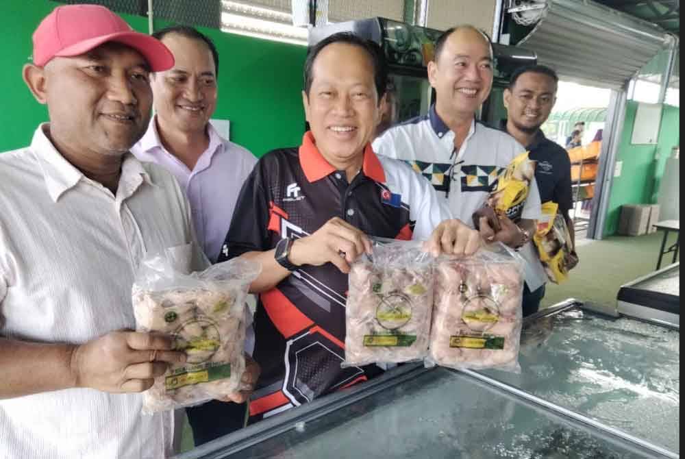 Ahmad (tengah) menunjukkan antara produk yang dijual di Pusat Jualan Peladang Outlet di Kampung Parit Yassin, Benut di Pontian.