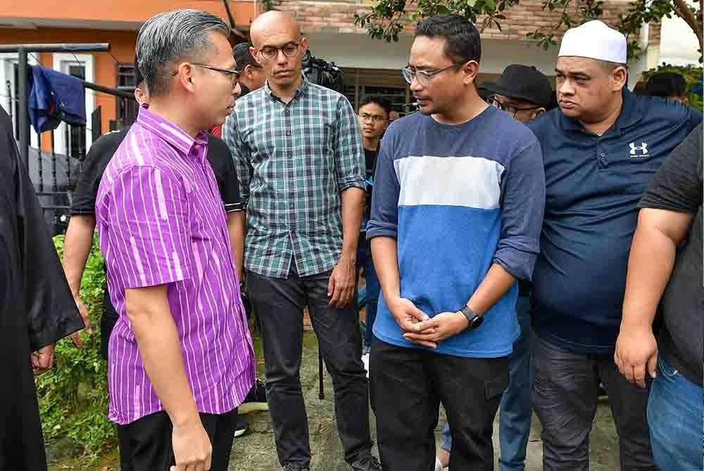 Fahmi Fadzil (kiri) beramah mesra bersama suami Allahyarham Siti Nor Hafiza Kamarudin Mohd Roshidi (dua dari kanan) ketika menziarahi keluarga wartawan hiburan itu pada Sabtu. Foto Bernama