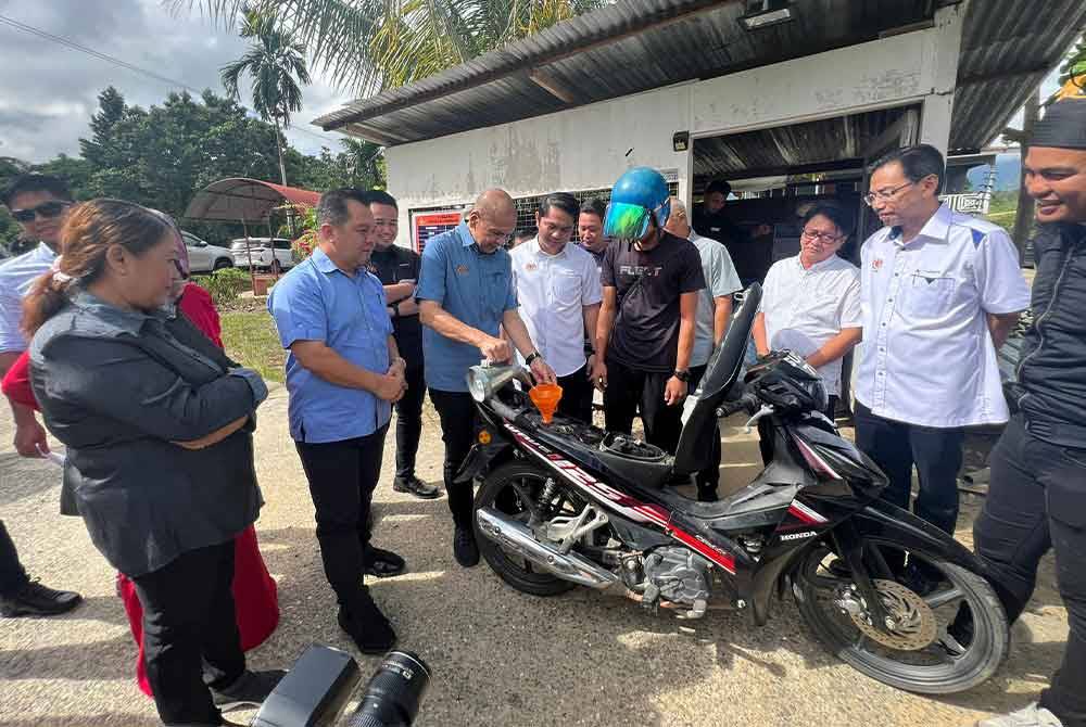 Armizan mengisi petrol sebuah motosikal ketika lawatan kerjanya dalam Program Community Drumming di Tenom.