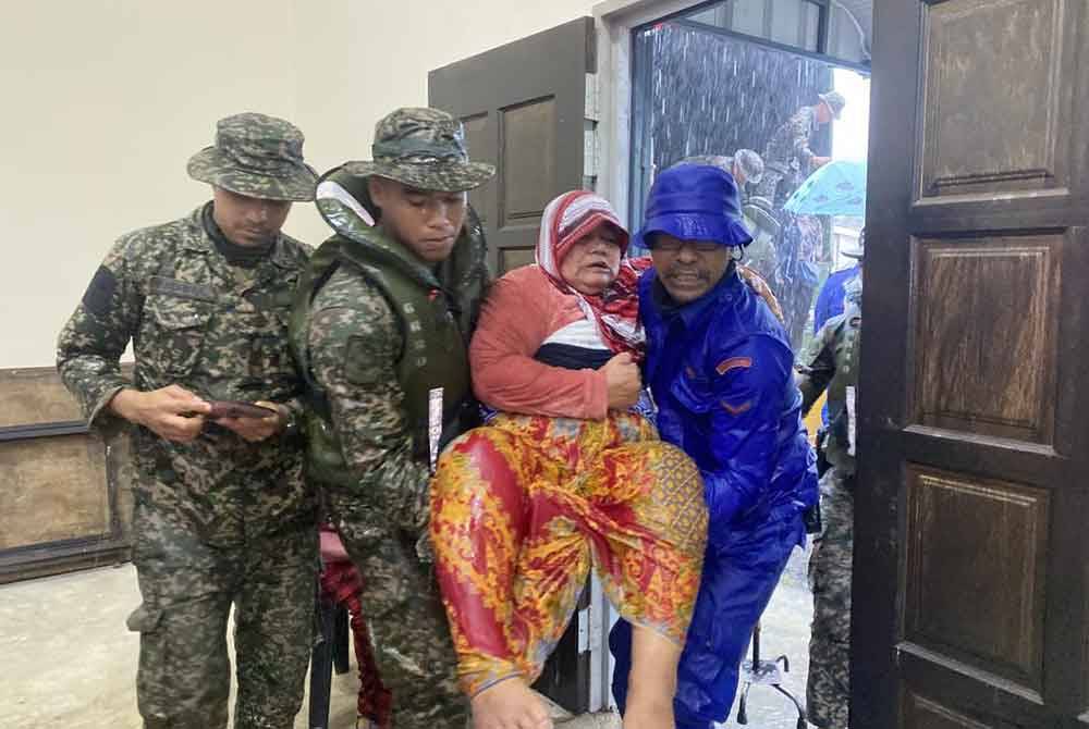 Anggota tentera dan APM membantu mangsa banjir di Kampung Tersusun, Kampung Seri Delima dan Kampung Seri Jaya, Johor Bahru berpindah pada Ahad. Foto ihsan APM