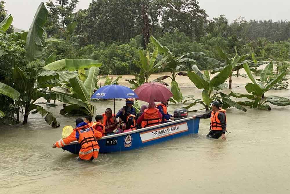 Anggota APM membantu mangsa banjir di Kampung Tersusun, Kampung Seri Delima dan Kampung Seri Jaya, Johor Bahru berpindah pada Ahad. Foto ihsan APM