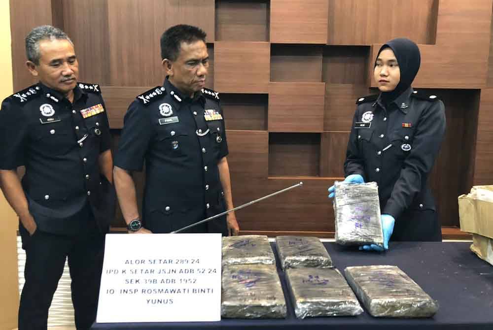 Fisol (tengah) menunjukkan ketulan ganja yang berjaya dirampas dalam dua serbuan berasingan di Kampung Kuala Alor, Simpang Kuala, di sini pada Khamis lalu.