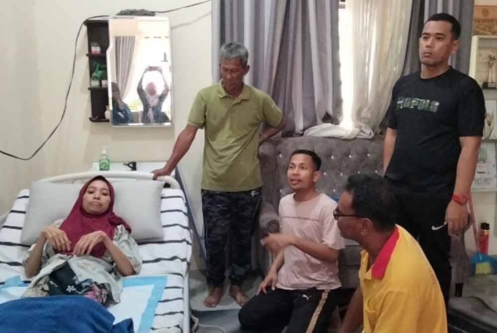Idhan (kanan) menerima sumbangan katil elektrik untuk Fatihah di kediaman mertuanya di Kampung Kubang Batang dekat sini.