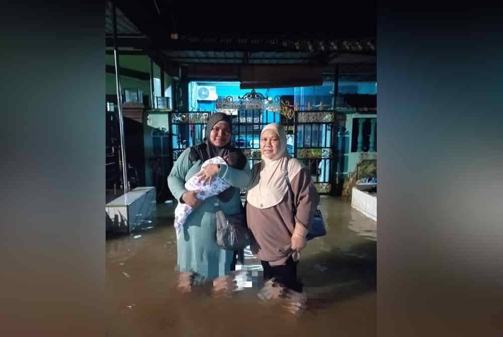 Nurul Nazurah (kiri) mendukung bayi bersama ibunya Rosmiati meredah banjir untuk ke PPS.