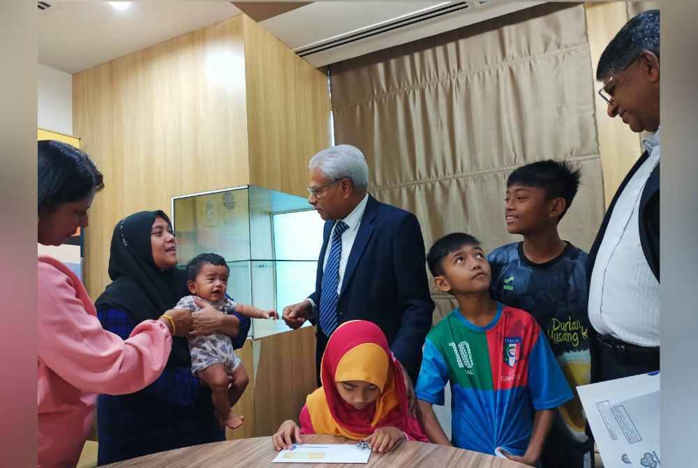 Sivanesan (tiga dari kiri) menyantuni Nursyakinah dan anak-anak sempena sesi penyerahan faedah pengurusan mayat PERKESO sebanyak RM2,000.