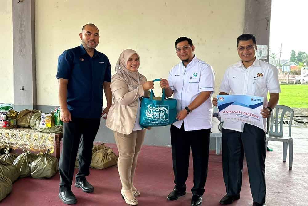 Majidah (dua dari kanan) menerima pek makanan yang disampaikan oleh Nik Mohd Nurul Ihsan (dua dari kanan) dan diiringi Muhd Nor Aswadi (kanan). Foto SINAR HARIAN