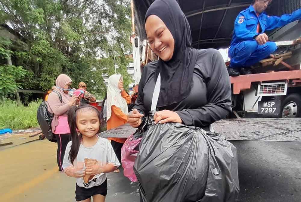 Noordiyana bersama anaknya diselamatkan pihak berkuasa selepas terperangkap dalam rumahnya kerana banjir di Taman Kemang, Kota Tinggi pada Isnin
