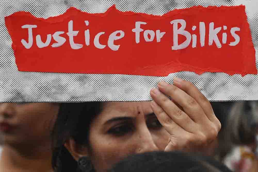 Seorang wanita memegang sepanduk ketika bantahan terhadap pembebasan lelaki yang disabitkan bersalah merogol beramai-ramai Bilkis Bano semasa rusuhan kaum 2002 di Gujarat, Mumbai pada 23 Ogos 2022. Foto fail AFP