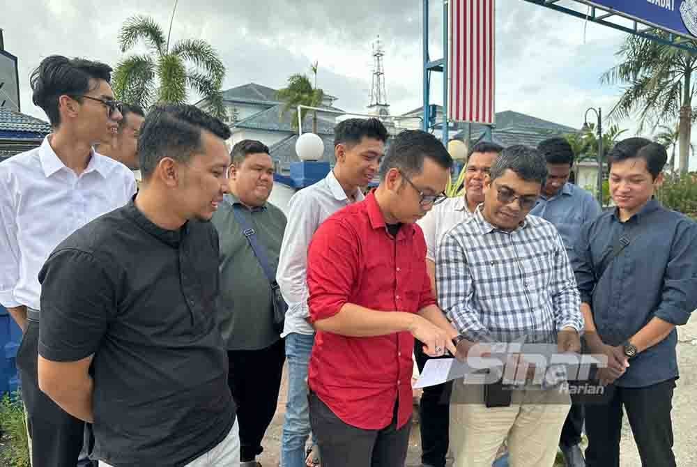 Mohamad Ezzat (dua dari kiri) melihat laporan polis berkait Langkah Dubai.