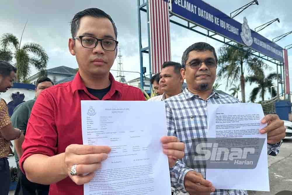 Mohamad Ezzat (kiri) menunjukkan laporan polis yang dibuat pada Isnin.