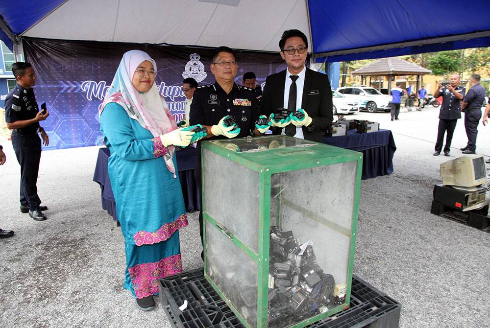 Mohamed Nordin (tengah) bersama Nurul Izalina dan Mohd Hairol melupuskan menunjukkan antara barang kes untuk dilupuskan.