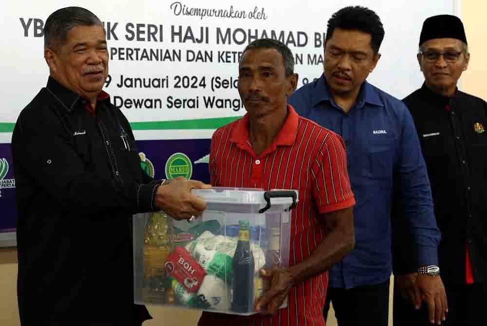 Mohamad menyampaikan barangan keperluan asas kepada golongan sasar pada Majlis Sentuhan Agro Madani Kelantan di Pusat Transformasi Luar Bandar Tunjung hari ini. Foto Bernama