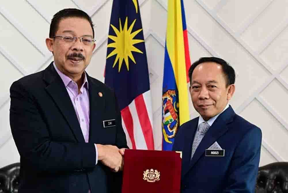 Mohd Zuki (kiri) menyerahkan watikah pelantikan kepada Rodzi.