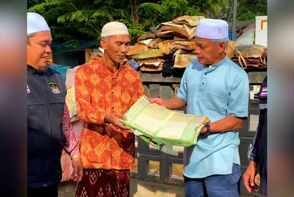 Muhammad Nasir (kanan) memeriksa al-Quran yang rosak bersama wakil Masjid Darul Falah, Narathiwat.
