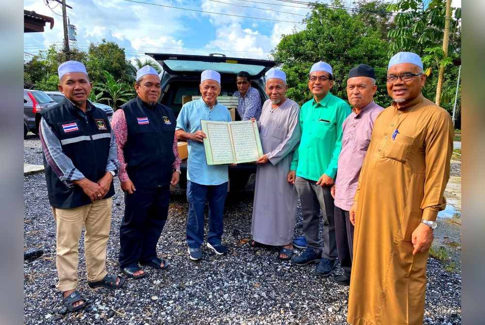 Muhammad Nasir (tiga dari kiri) menyerahkan sumbangan al-Quran kepada Imam Masjid Indarabihim, Kampung Tamdok, Mat Salleh Ismail (empat dari kanan).