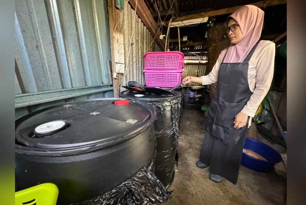 Surina menunjukkan bekalan air yang disimpan untuk kegunaan gerainya sepanjang gangguan bekalan air berjadual di Pulau Pinang.