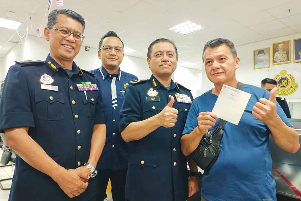 Aedy Fadly (dua dari kanan) melihat cetakan slip penbaharuan LMM milik CK Khong, 60, (kanan) ketika tinjauan di Pusat Transformasi Bandar (UTC) Perak di Ipoh pada Rabu.