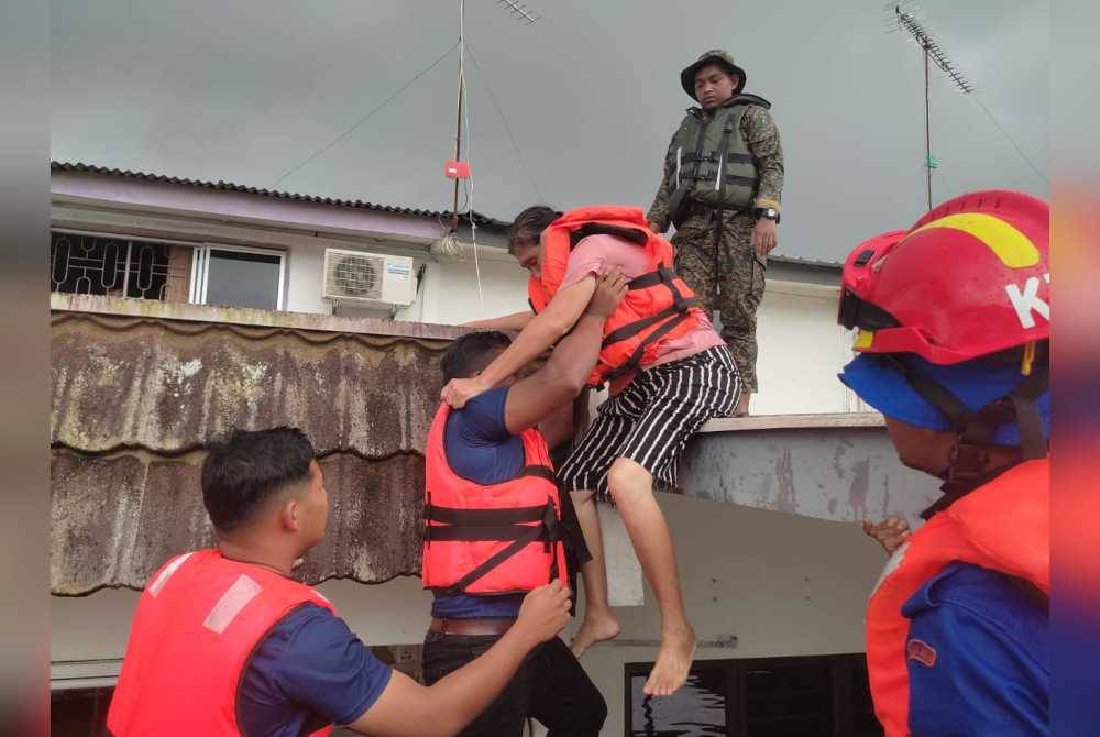Anggota bomba melakukan kerja-kerja pemindahan mangsa banjir yang terperangkap di rumah selepas dinaiki banjir di bandar Kota Tinggi.