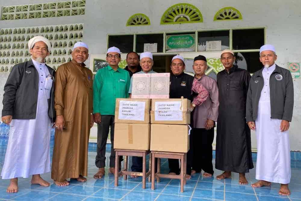 Muhammad Nasir (empat dari kiri) mengagihkan al-Quran kepada wakil-wakil masjid di Narathiwat.